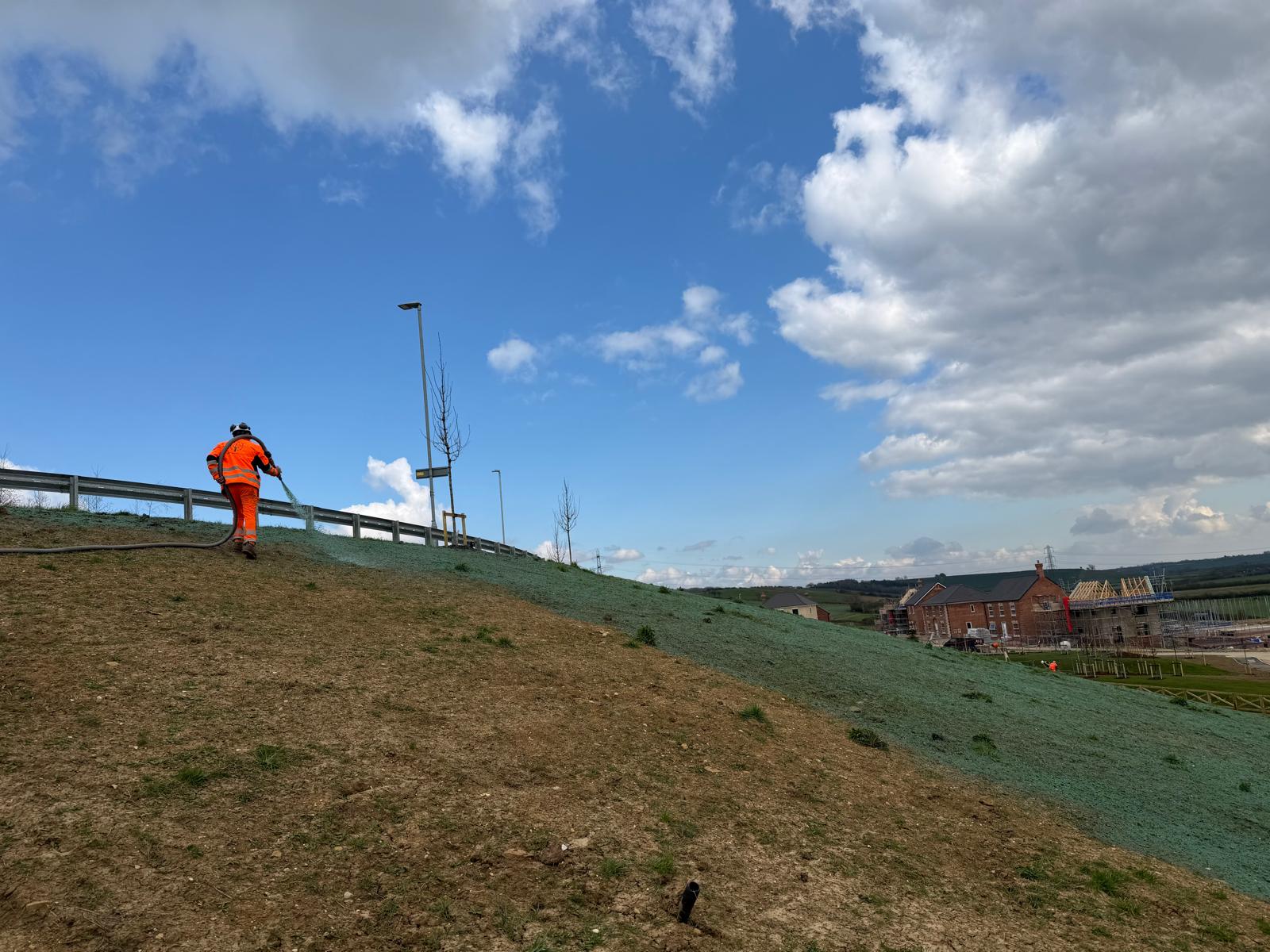 man in Hi-Vis jacket spraying hydroseeding on bank