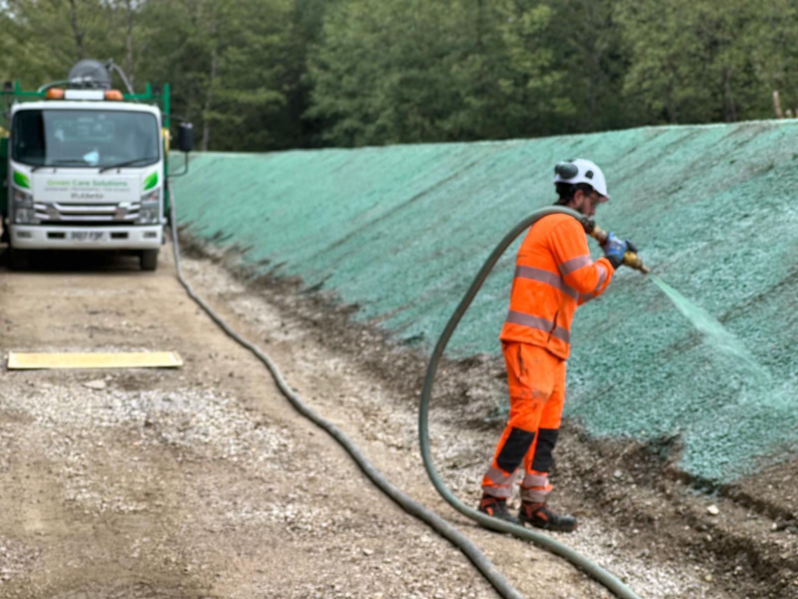 Man spraying hydroseed on grass verge